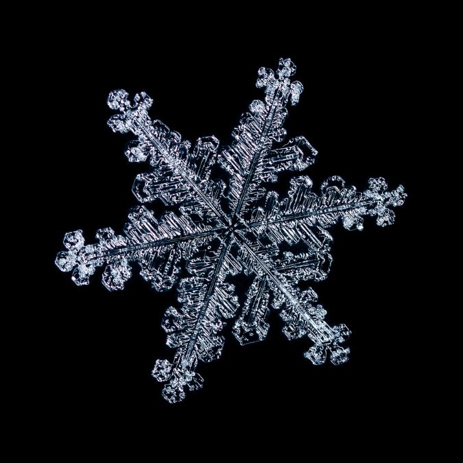 Macro photograph of a snowflake showing hexagonal crystal symmetry
