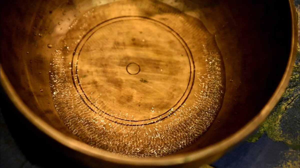 Water cymatics in a singing bowl showing concentric ring patterns from vibration